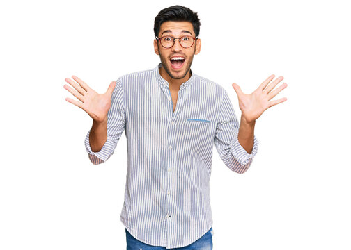 Young handsome man wearing casual clothes and glasses celebrating crazy and amazed for success with arms raised and open eyes screaming excited. winner concept