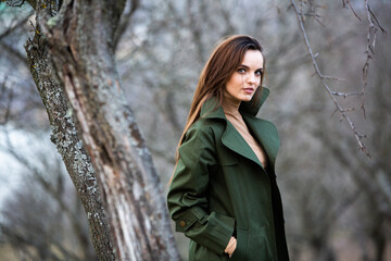 Image of young beautiful woman wearing rain jacket in cold weather. Thinker european girl in spring nature.