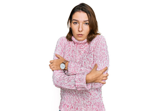 Young caucasian girl wearing wool winter sweater shaking and freezing for winter cold with sad and shock expression on face