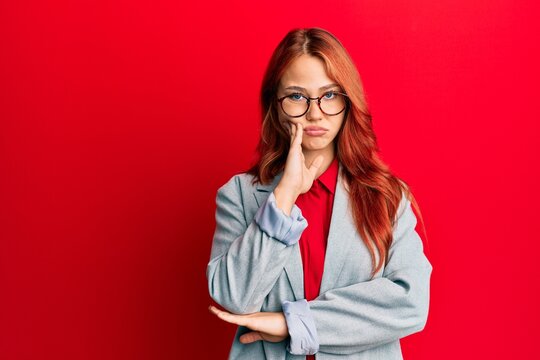 Young redhead woman wearing business jacket and glasses thinking looking tired and bored with depression problems with crossed arms.