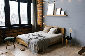 Double bed with natural natural accents on the sheets and beige pillows in the grey Scandinavian...