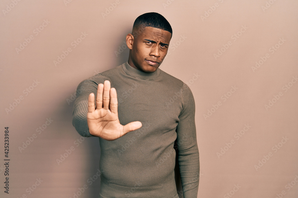 Wall mural young black man wearing casual turtleneck sweater doing stop sing with palm of the hand. warning exp