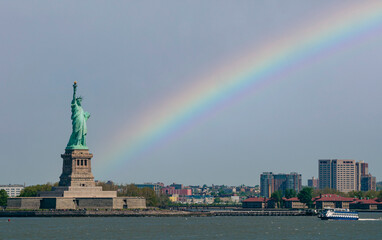 Statue of liberty in new york city and a rainbow in the sky on the background
