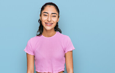 Hispanic teenager girl with dental braces wearing casual clothes with a happy and cool smile on...