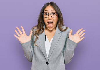 Young brunette woman wearing business clothes celebrating crazy and amazed for success with arms raised and open eyes screaming excited. winner concept