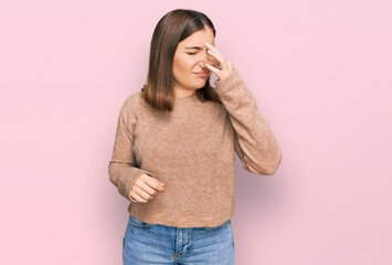 Young beautiful woman wearing casual clothes smelling something stinky and disgusting, intolerable smell, holding breath with fingers on nose. bad smell - obrazy, fototapety, plakaty