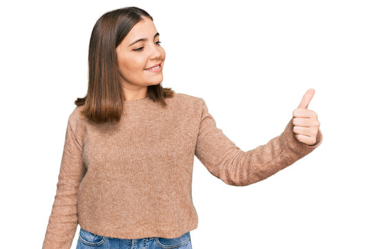 Young beautiful woman wearing casual clothes looking proud, smiling doing thumbs up gesture to the side