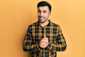 Young hispanic man wearing casual clothes with hands together and crossed fingers smiling relaxed and cheerful. success and optimistic