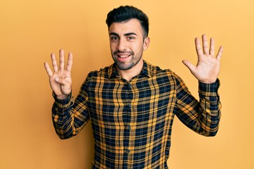 Naklejka premium Young hispanic man wearing casual clothes showing and pointing up with fingers number nine while smiling confident and happy.