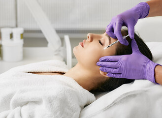 Obraz na płótnie Canvas Beautiful woman during facial mesotherapy. Beautician doing anti-aging injection for tightening skin and remove eye wrinkles