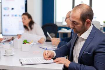 Businessman reading paper document, discussing contract with confident partner, signing investment papers. Executive director meeting shareholders in start up office, making satisfactorily agreement.