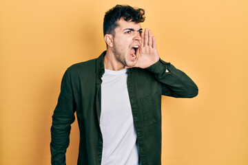 Young hispanic man wearing casual clothes shouting and screaming loud to side with hand on mouth. communication concept.