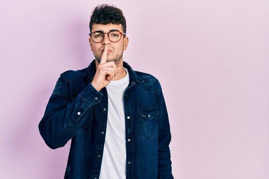 Young hispanic man wearing casual clothes and glasses asking to be quiet with finger on lips. silence and secret concept.