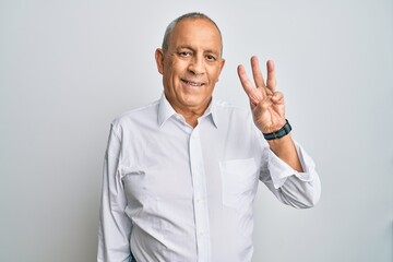 Handsome senior man wearing casual white shirt showing and pointing up with fingers number three while smiling confident and happy.