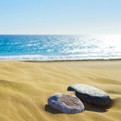 Fototapeta na wymiar Two stones on the sandy shore of the ocean. Square orientation.
