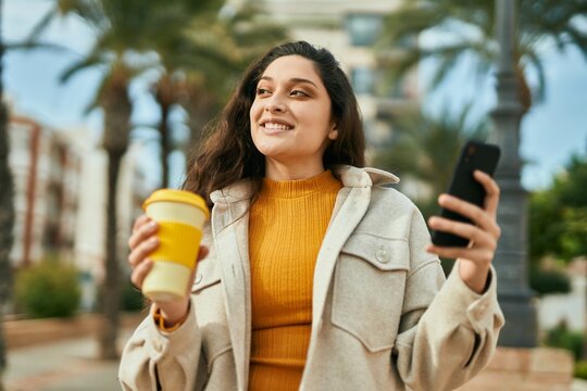 Young middle east woman using smartphone drinking coffee at the city.