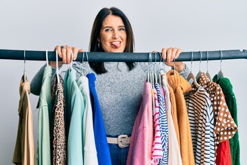 Middle age brunette woman working as professional personal shopper sticking tongue out happy with funny expression.