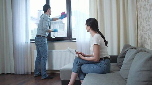 Henpecked husband washes the window, and the wife reads a book