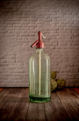 Moody dark food photography of an antique soda siphon of glass on a wood table. Still life image...