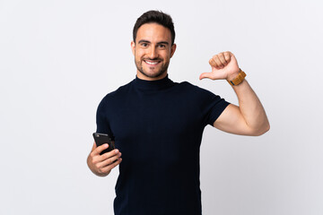 Young caucasian man using mobile phone isolated on white background proud and self-satisfied