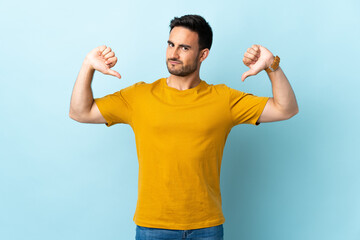 Young handsome man over isolated background showing thumb down with two hands