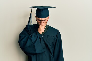 Young caucasian man wearing graduation cap and ceremony robe feeling unwell and coughing as symptom for cold or bronchitis. health care concept.