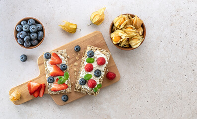 Rye oats crispbread with cottage cheese, mint leaves, fresh strawberries, and blueberries. Top...