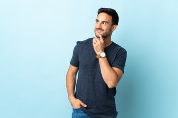 Young handsome man over isolated background looking up while smiling