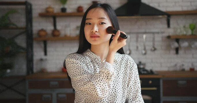 Asian korean beauty blogger woman filming daily makeup routine tutorial. Influencer lady live streaming cosmetics product review in home studio