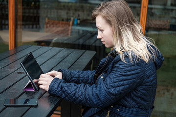 Young woman using her tablet sitting at table in a terrace close to Waterloo  bridge in London....