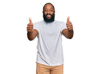 Young african american man wearing casual white tshirt approving doing positive gesture with hand, thumbs up smiling and happy for success. winner gesture.