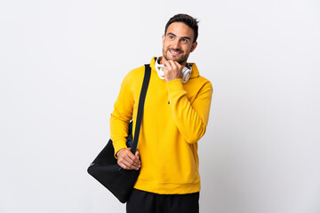 Young sport man with sport bag isolated on white background looking up while smiling