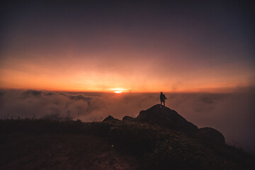 silhouette of a person on top of the mountain above the clouds - 425244179