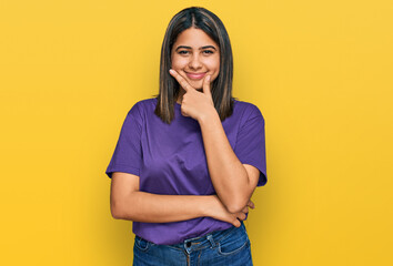 Young hispanic girl wearing casual purple t shirt looking confident at the camera smiling with crossed arms and hand raised on chin. thinking positive.