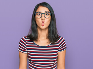 Beautiful asian young woman wearing casual clothes and glasses making fish face with lips, crazy and comical gesture. funny expression.