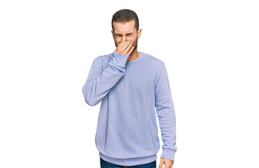 Fototapeta premium Young caucasian man wearing casual clothes smelling something stinky and disgusting, intolerable smell, holding breath with fingers on nose. bad smell