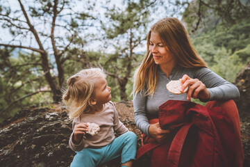 Family lifestyle mother and daughter child outdoor in forest on picnic eating rice cookies travel...