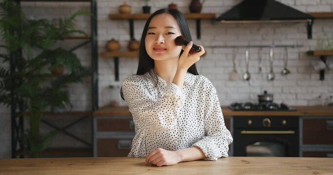 Asian korean beauty blogger woman filming daily makeup routine tutorial. Influencer lady live streaming cosmetics product review in home studio