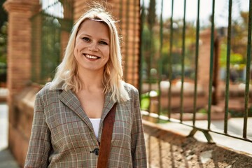 Young blonde businesswoman smiling happy standing at the city.