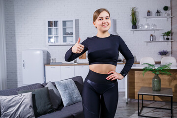 Fototapeta na wymiar A beautiful athletic woman in a black top and leggings demonstrates a slender figure. Motivation to go in for sports. Healthy lifestyle.