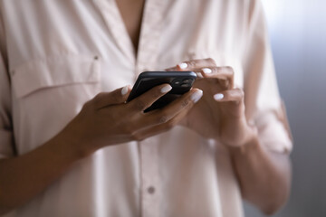 Crop close up of African American woman hold use modern smartphone gadget browse wireless internet on device. Biracial female text message on cellphone. Technology, communication concept.