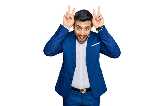 Young hispanic man wearing business jacket posing funny and crazy with fingers on head as bunny ears, smiling cheerful