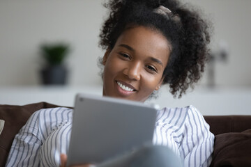 Close up of smiling biracial woman use tablet talk speak on video call on gadget at home. Happy African American female have webcam digital online conference on tab. Virtual event concept.