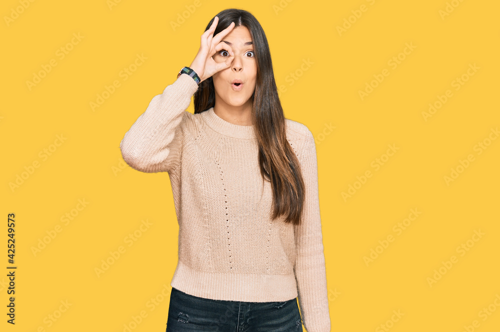 Sticker young brunette woman wearing casual winter sweater doing ok gesture shocked with surprised face, eye