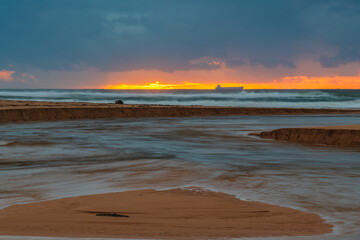 Rainy day sunrise at the lagoon with ship on the horizon