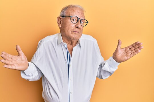 Senior caucasian man wearing casual clothes and glasses clueless and confused with open arms, no idea and doubtful face.