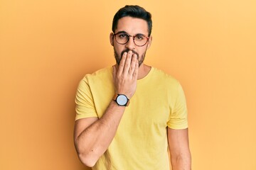 Young hispanic man wearing casual clothes and glasses bored yawning tired covering mouth with hand. restless and sleepiness.