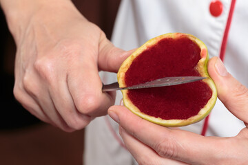 The woman cuts berry jelly in apple mold.