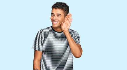 Young handsome african american man wearing casual clothes smiling with hand over ear listening an hearing to rumor or gossip. deafness concept.