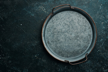 Old retro metal tray on a black stone background. Top view. Free copy space.